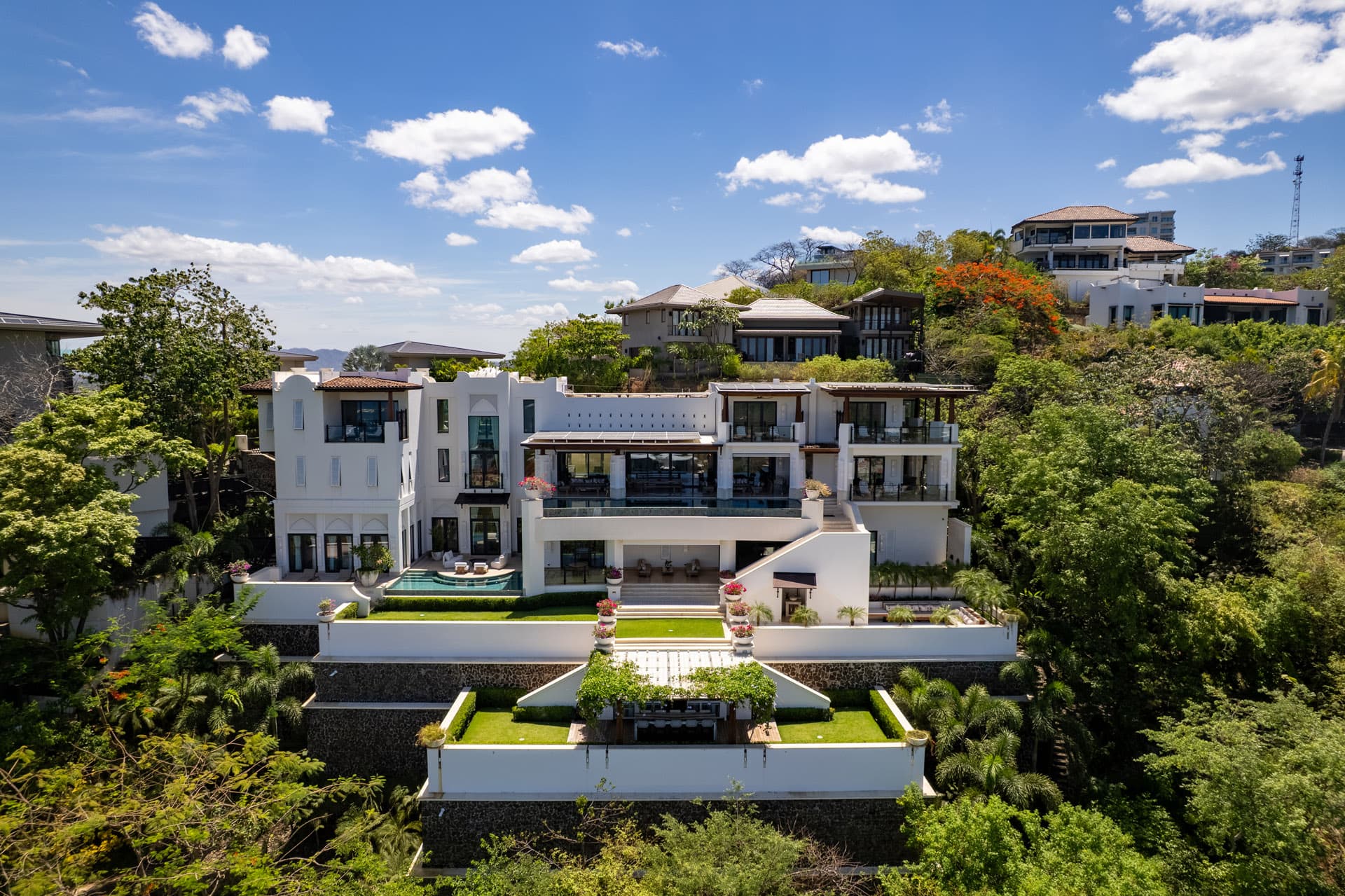 Full facade from above — pool, gardens, and terraced levels