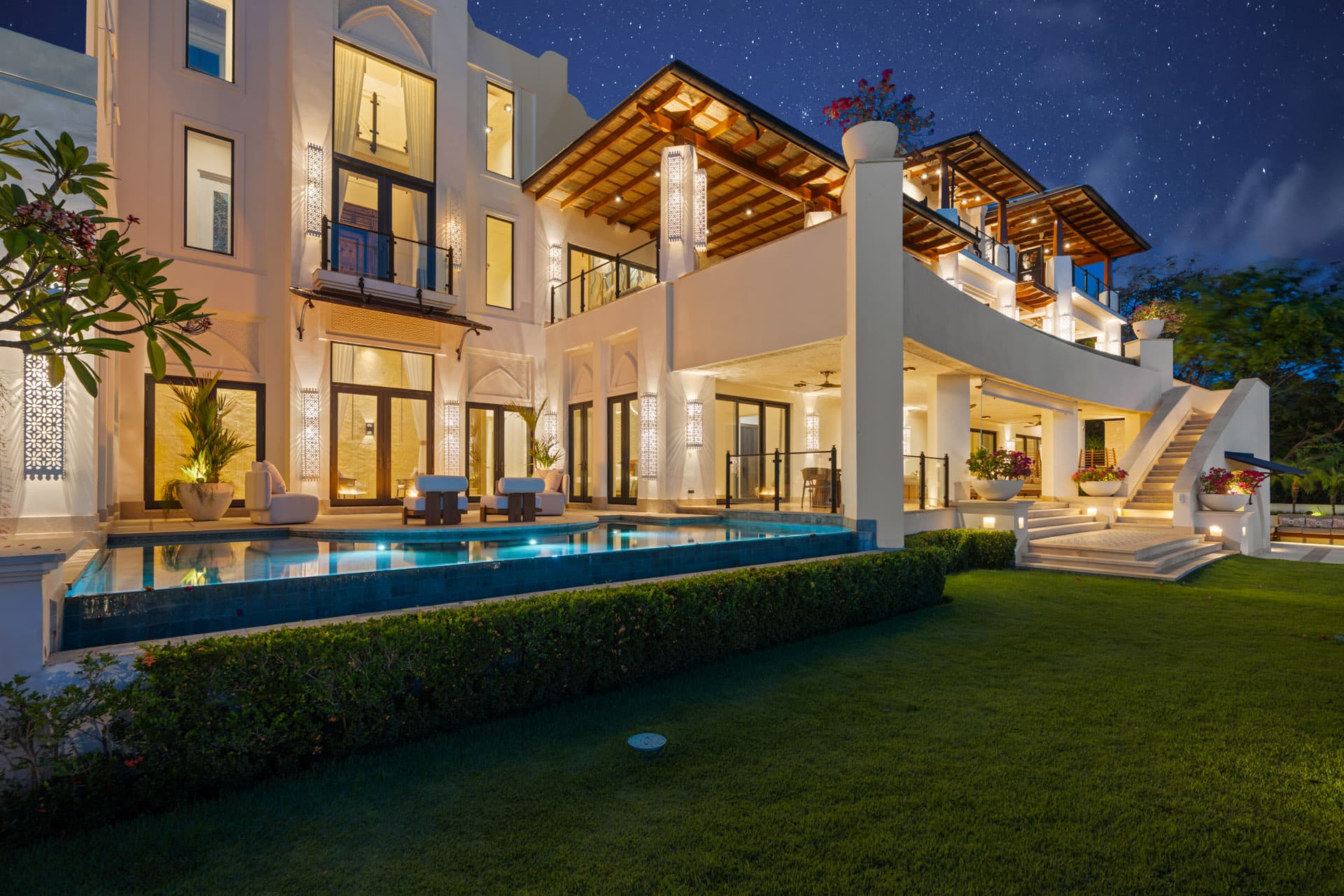 Villa Luciérnaga illuminated at night, pool glowing blue beneath a starry sky