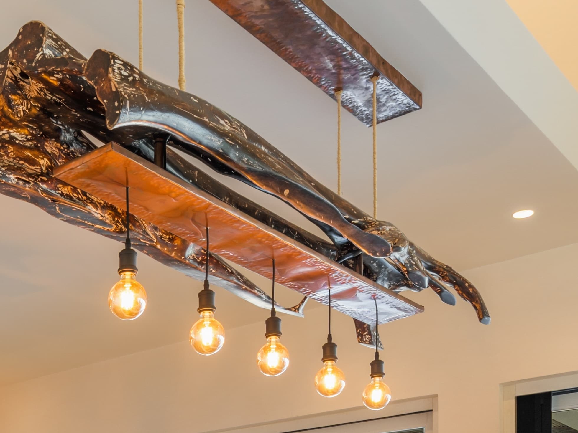 Matapalo chandelier -- a linear fixture sculpted by Abraham Valenzuela from the hollow woody shell of a Matapalo vine, with a copper trough and five Edison globe bulbs