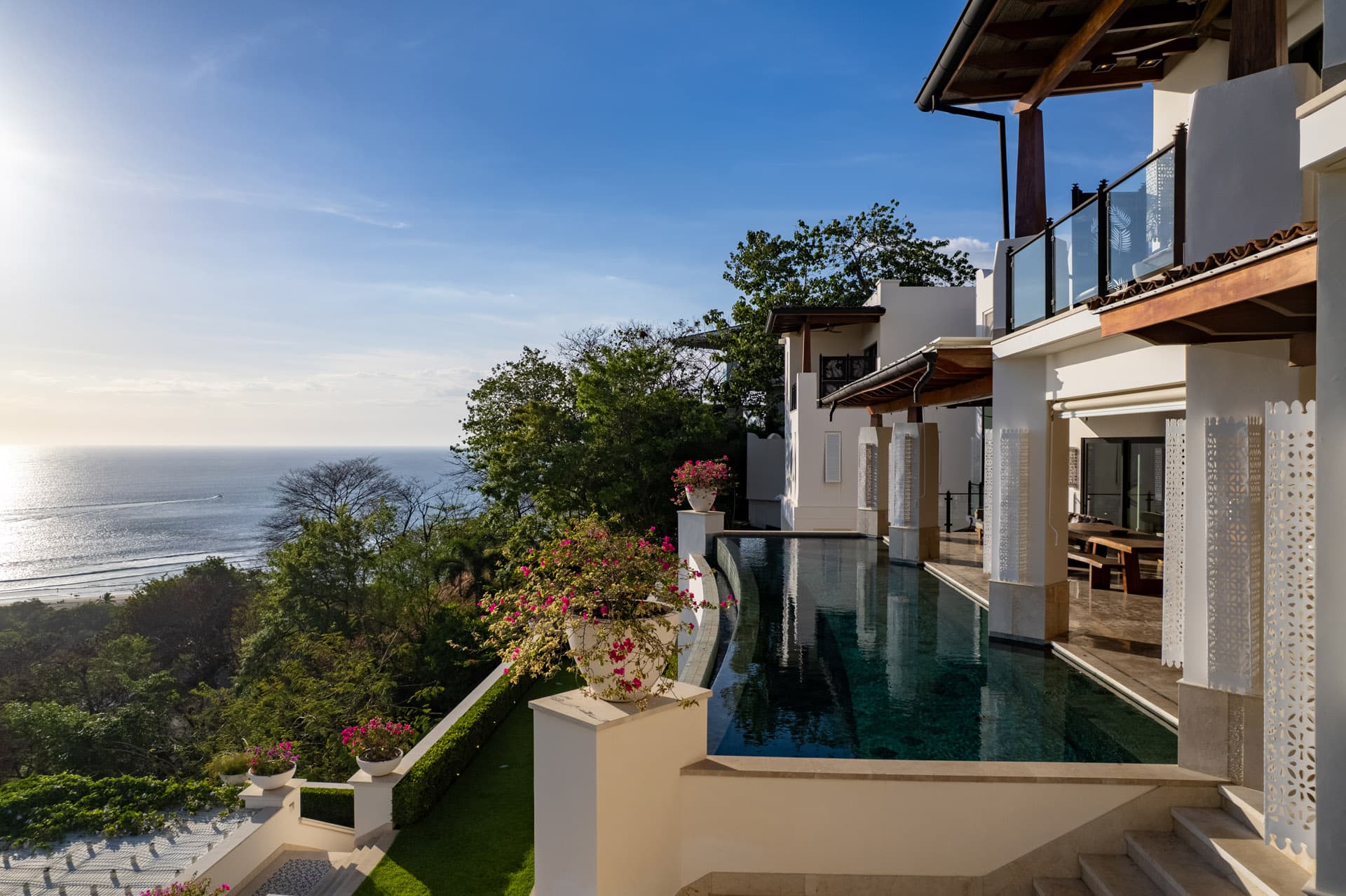 Infinity pool edge with bougainvillea in morning light, Pacific beyond