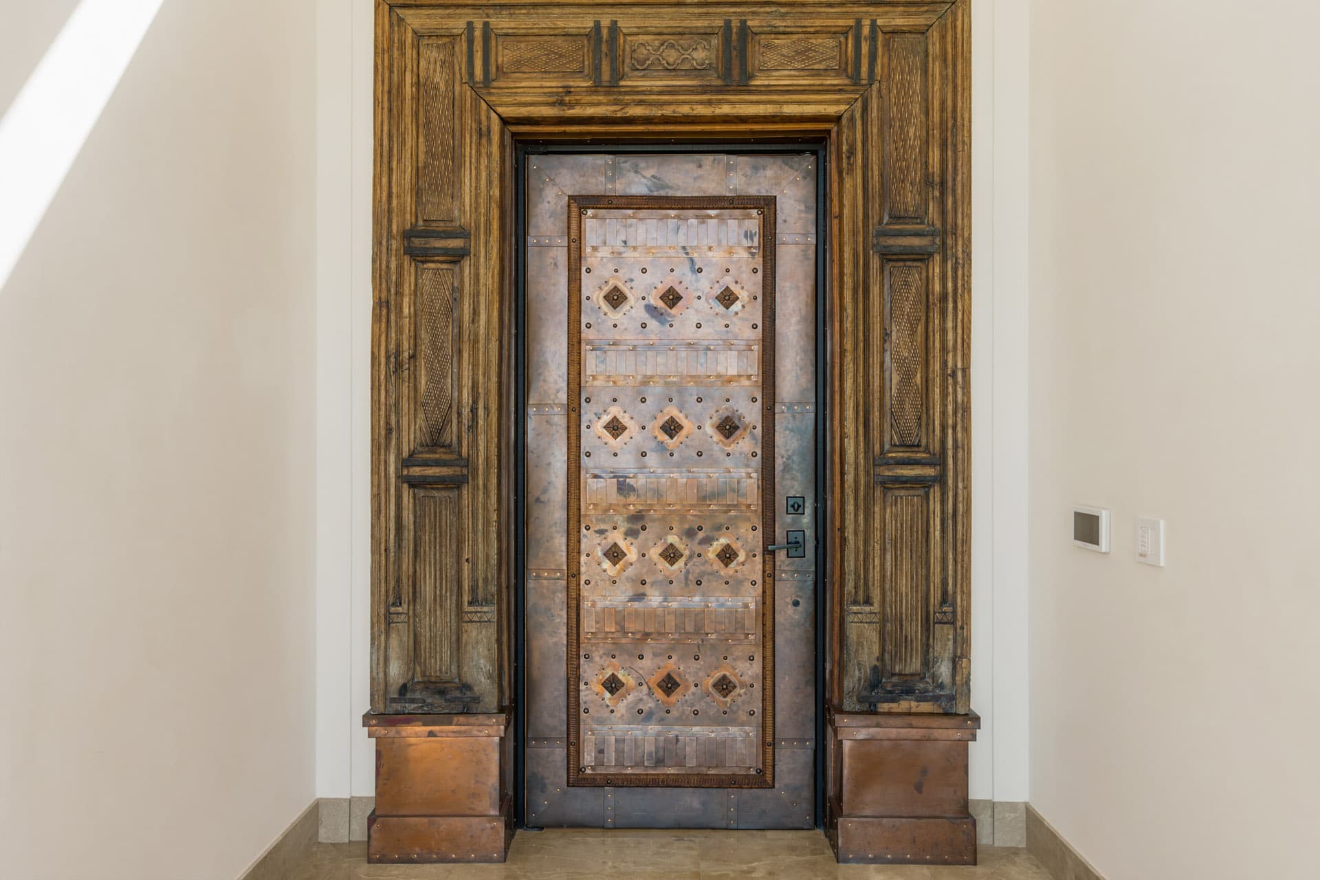 Villa Luciérnaga front entrance from inside -- antique hand-carved wood frame from India surrounding the copper door with geometric bronze inlays