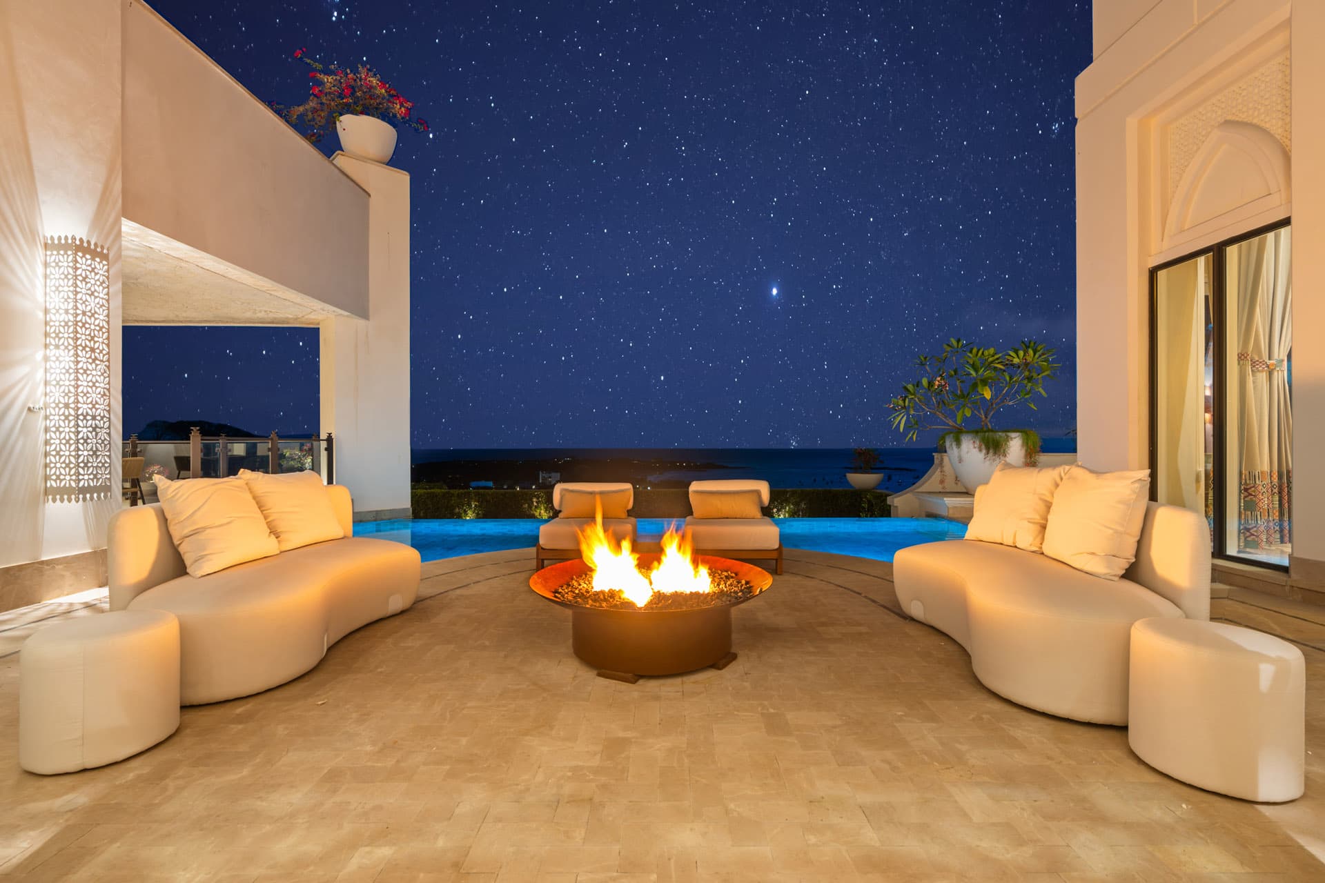 Fire pit glowing under a starry sky at Villa Luciérnaga, infinity pool beyond