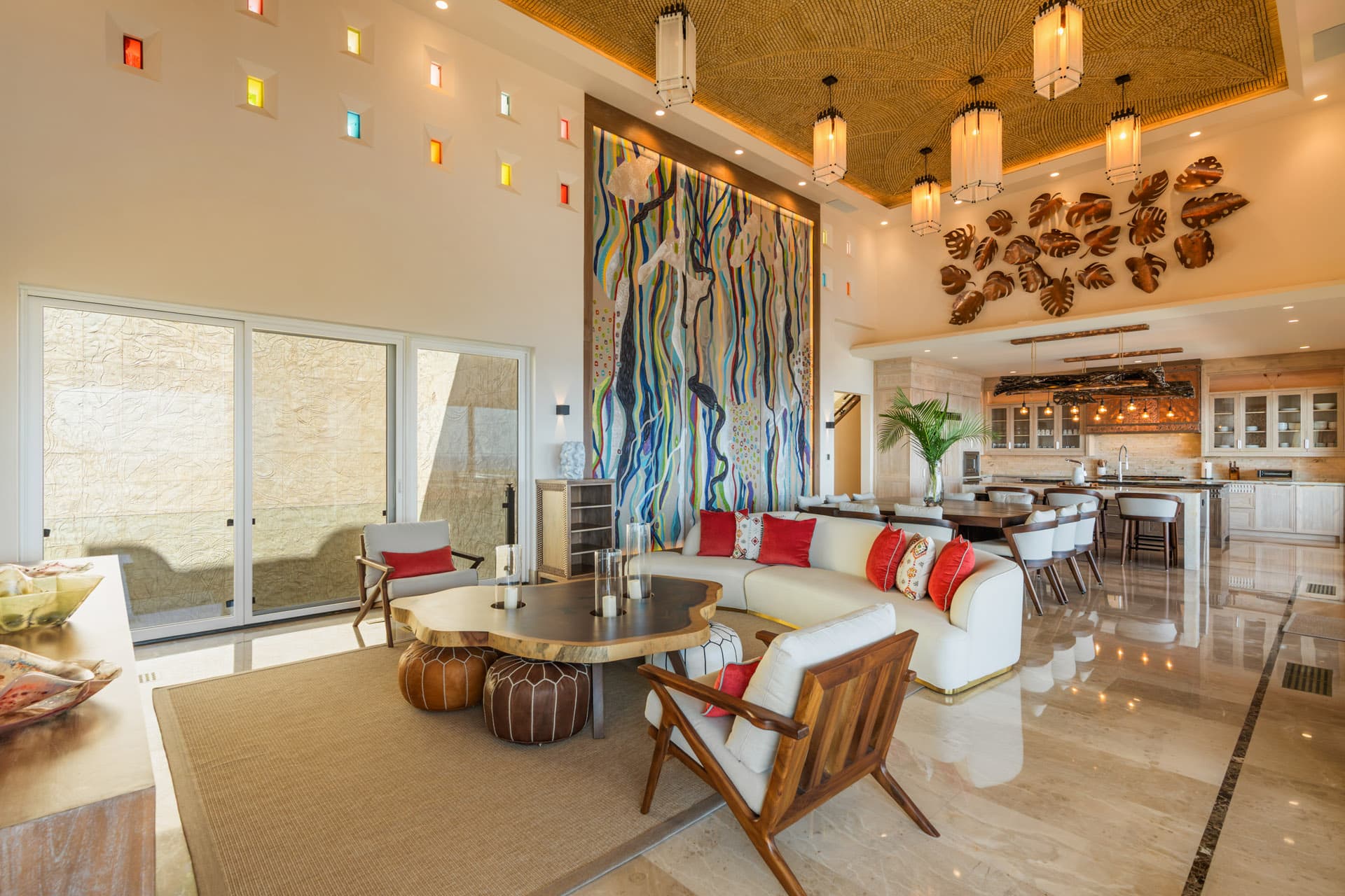 Great room at Villa Luciérnaga — Abraham Valenzuela's large-scale canvas, copper monstera leaf wall art, colorful light niches, and woven arabesque ceiling