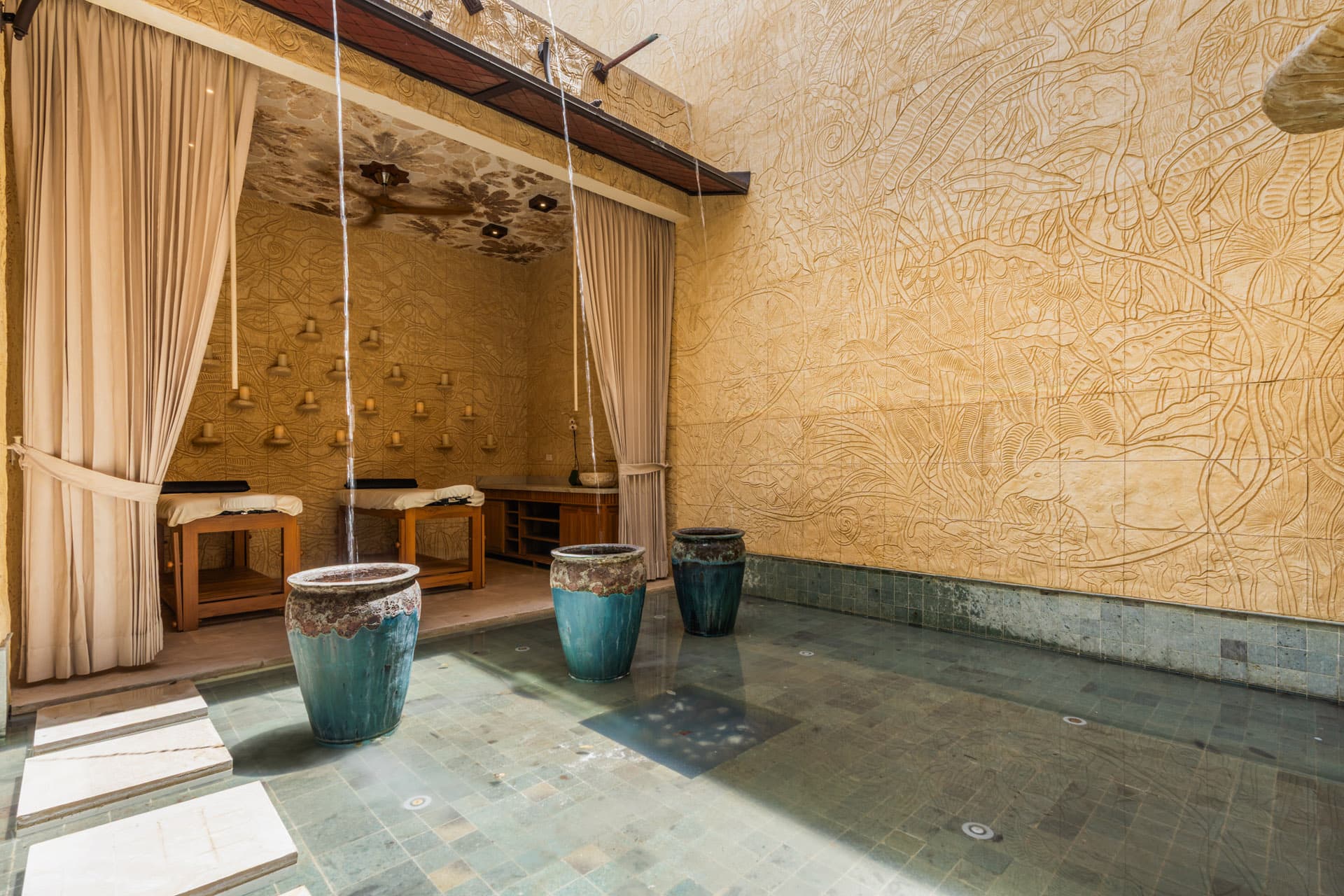 Massage alcove and fountain courtyard — carved bas relief walls, ceramic urns, and leaf-impression ceiling