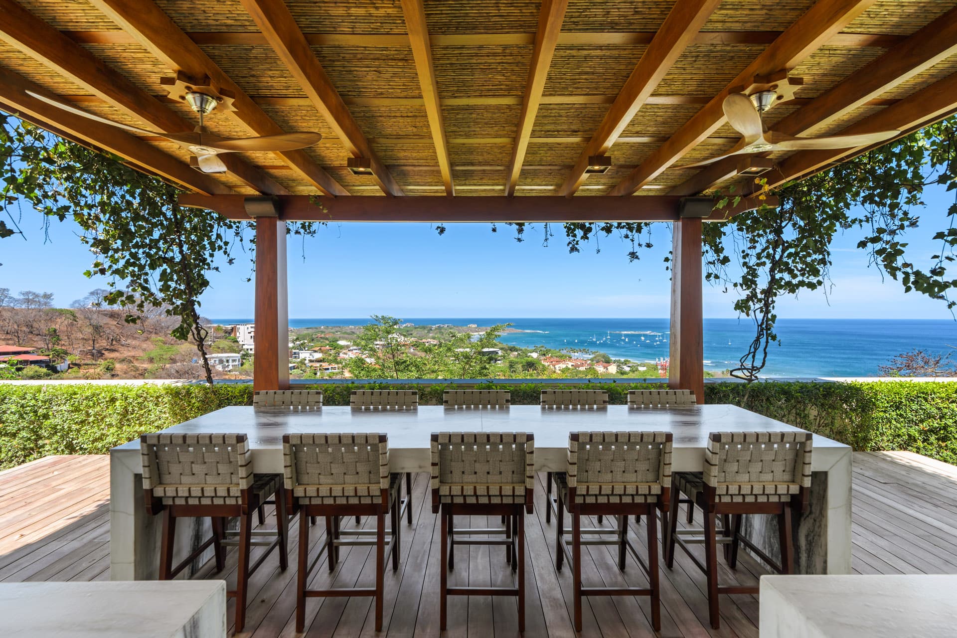 Outdoor bar and dining beneath the pergola, ocean beyond
