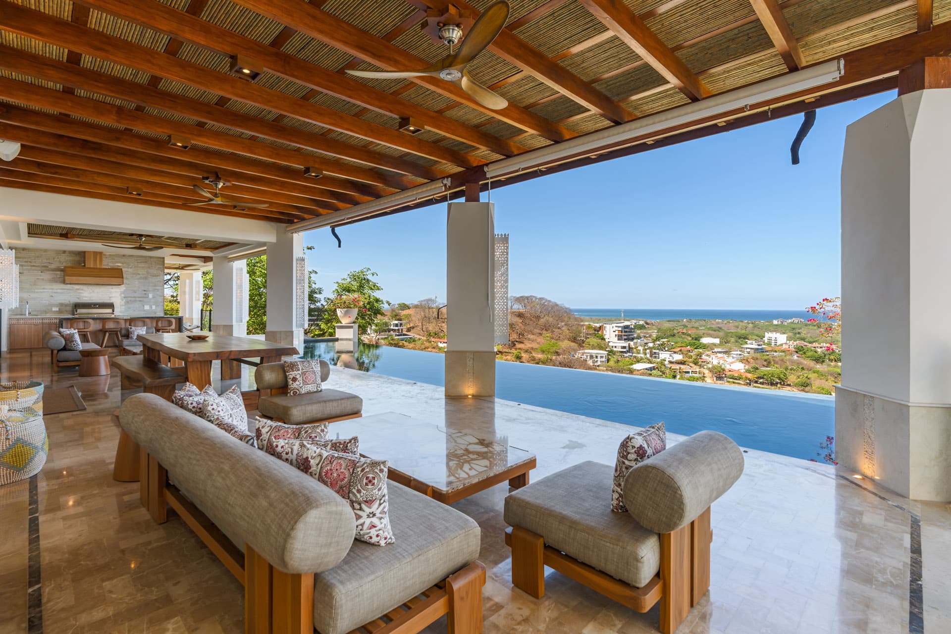 Covered terrace lounge — open-air living with infinity pool and ocean view